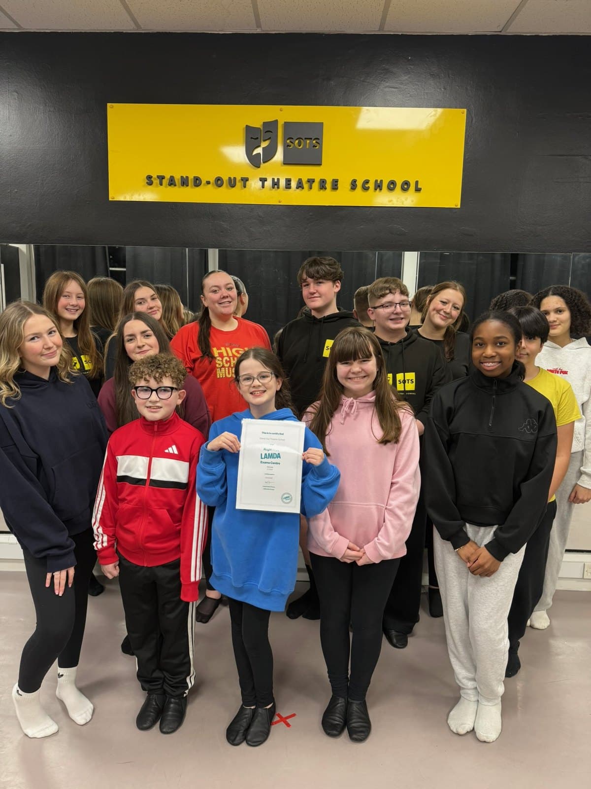 Advanced Musical Theatre class grouped under the Stand-Out Theatre School studio sign