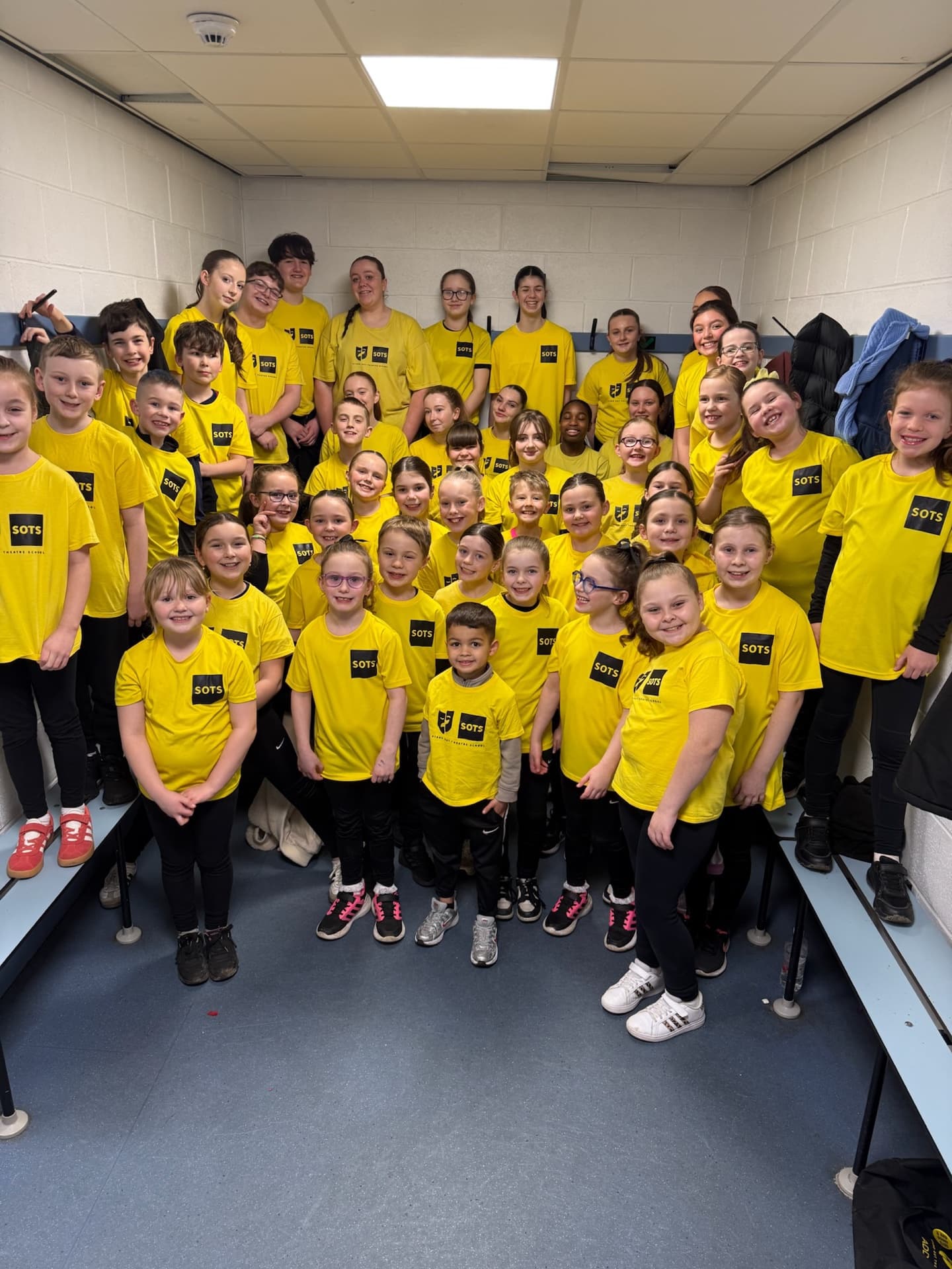 Big group of SOTS students backstage at Falkirk Stadium in their yellow Stand-Out t-shirts
