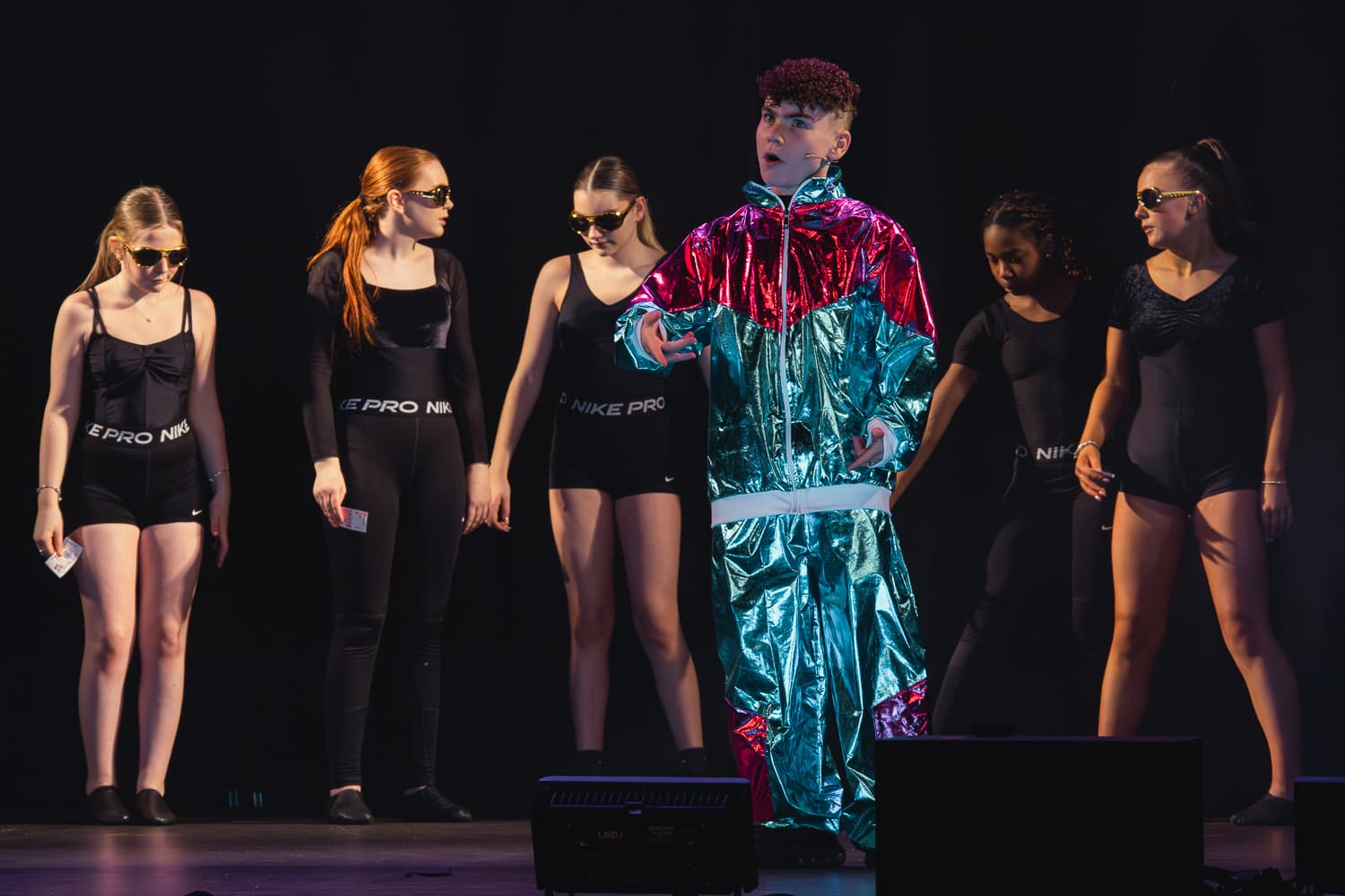 Cast on stage with a featured soloist in a metallic costume