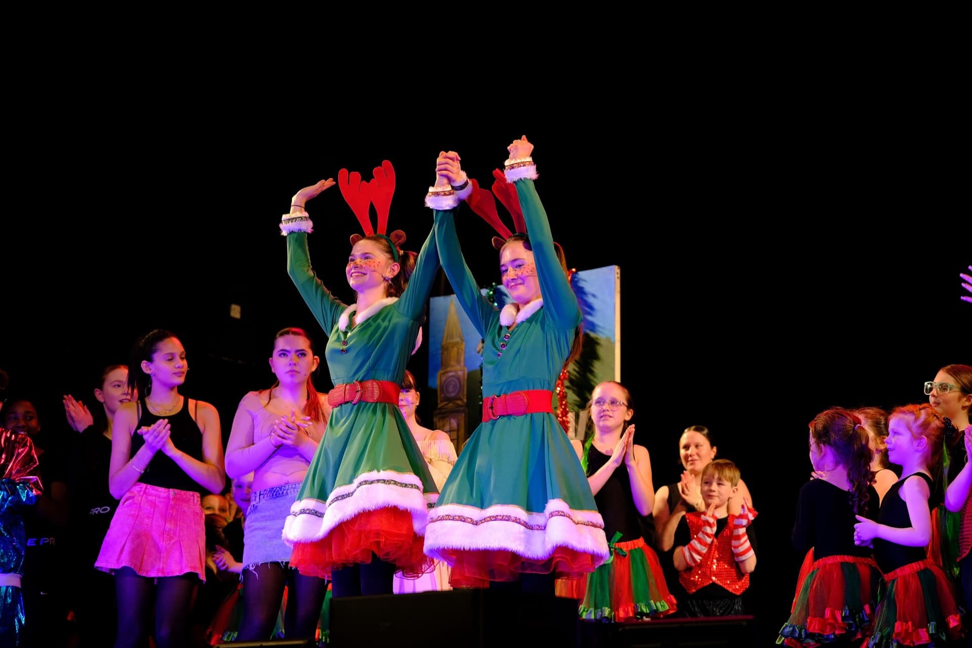 Two performers in elf costumes mid-bow during the Christmas pantomime