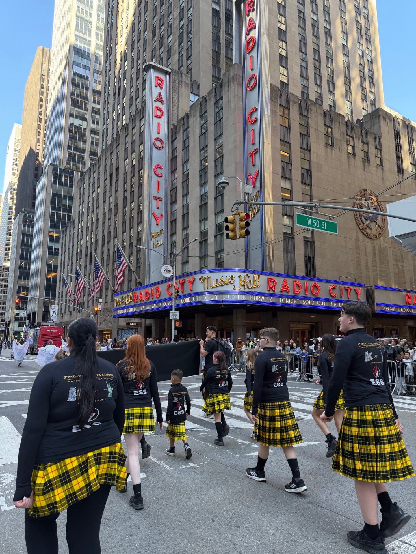 SOTS students in tartan kilts walking past Radio City Music Hall on the NYC Tartan Day Parade