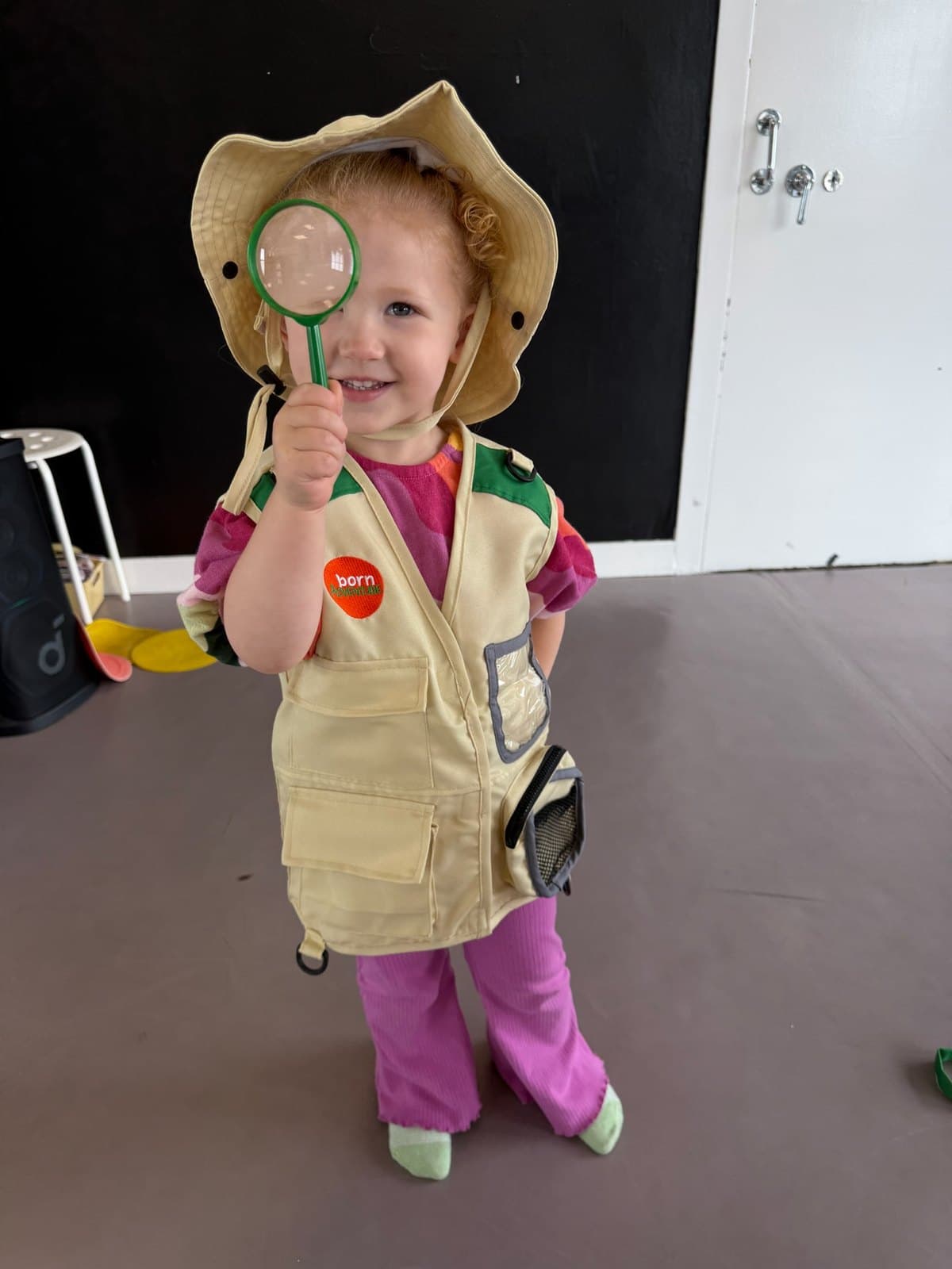Preschool student in an explorer hat and waistcoat holding a magnifying glass