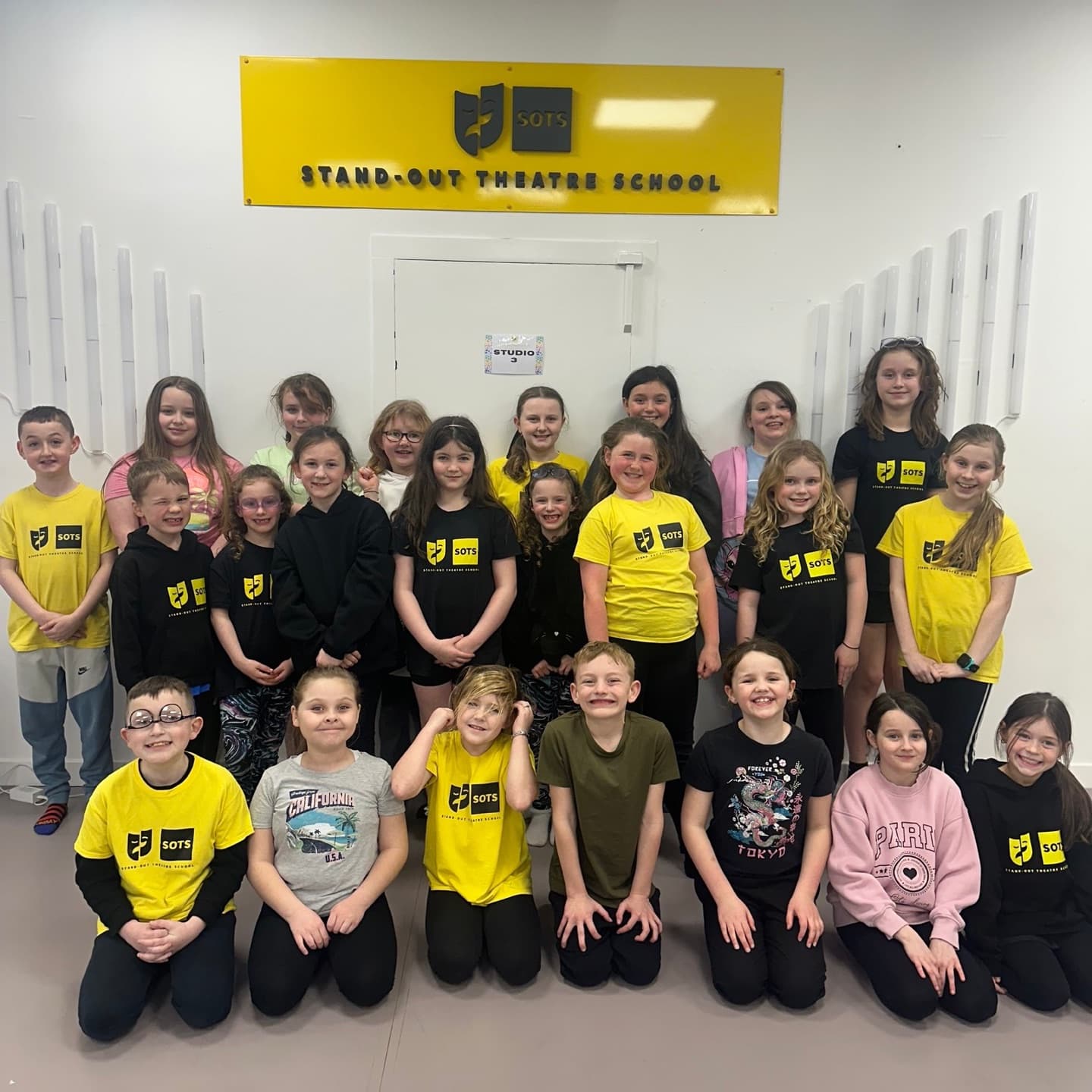 Group of students under the Stand-Out Theatre School studio sign