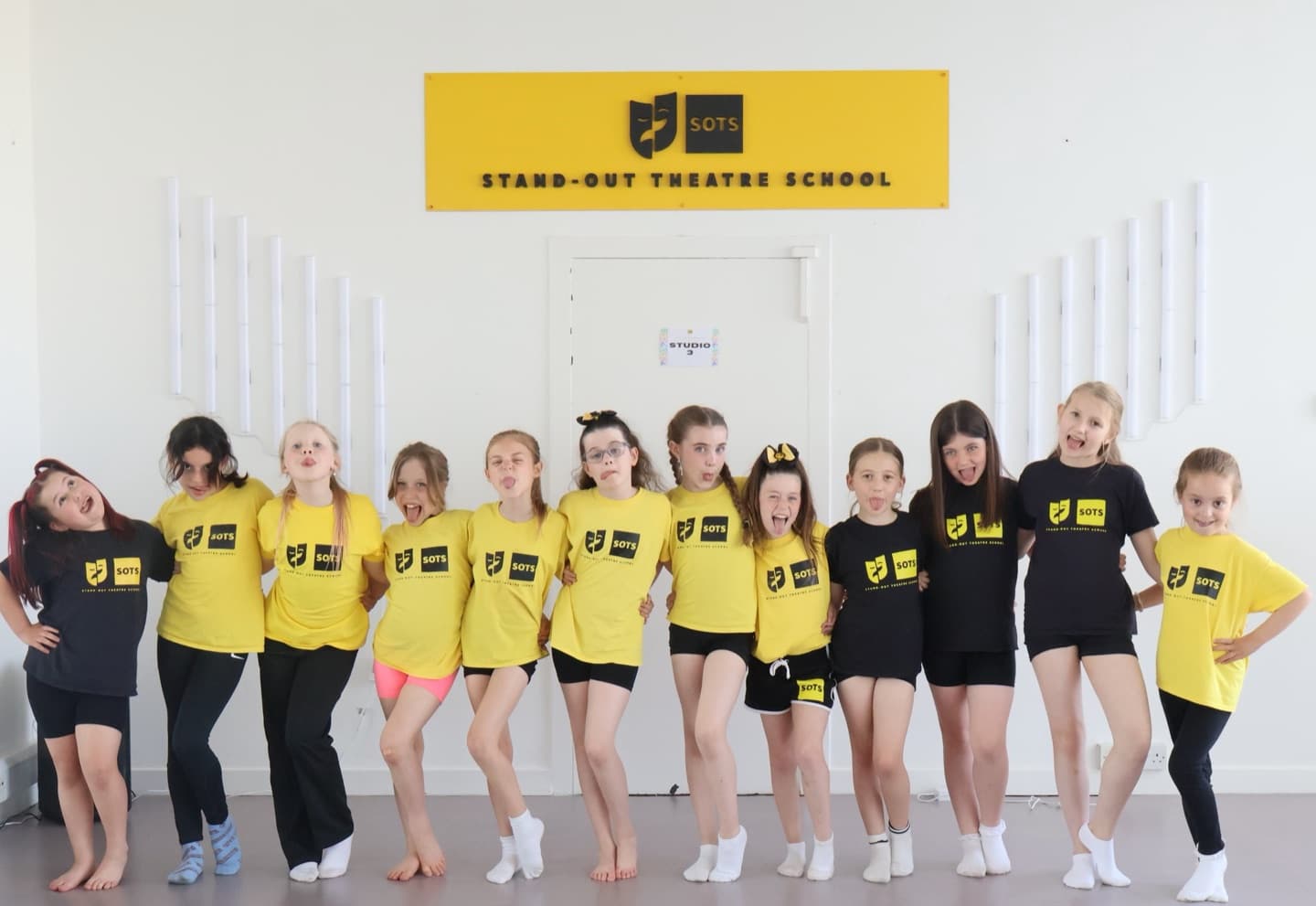 Junior class lined up under the studio sign sticking tongues out